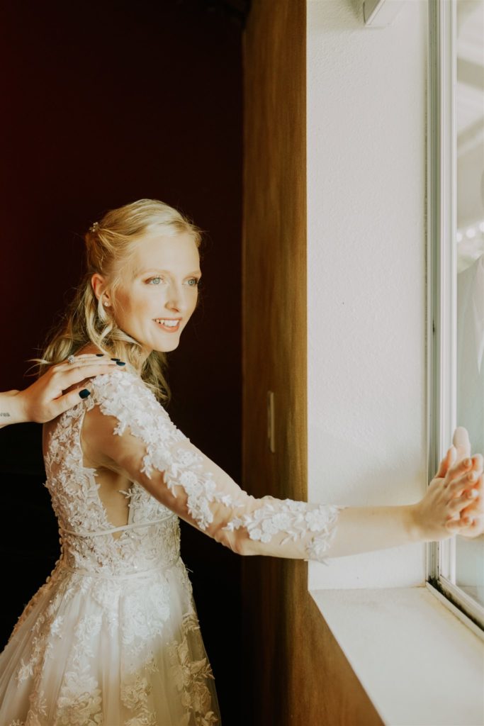 bride touching husband's hand through window during prayer before tucker hill wedding