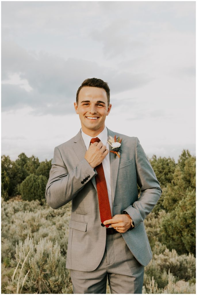 groom adjusting tie smiling at camera