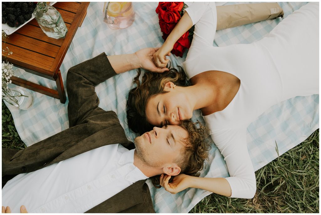 couple laying down cuddling after picnic lunch