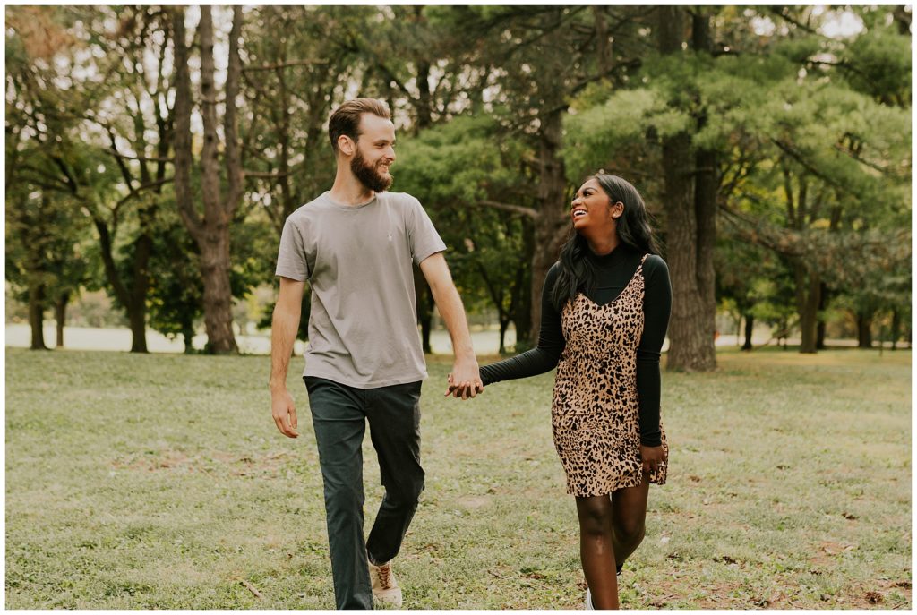 couple walking in field during engagement session