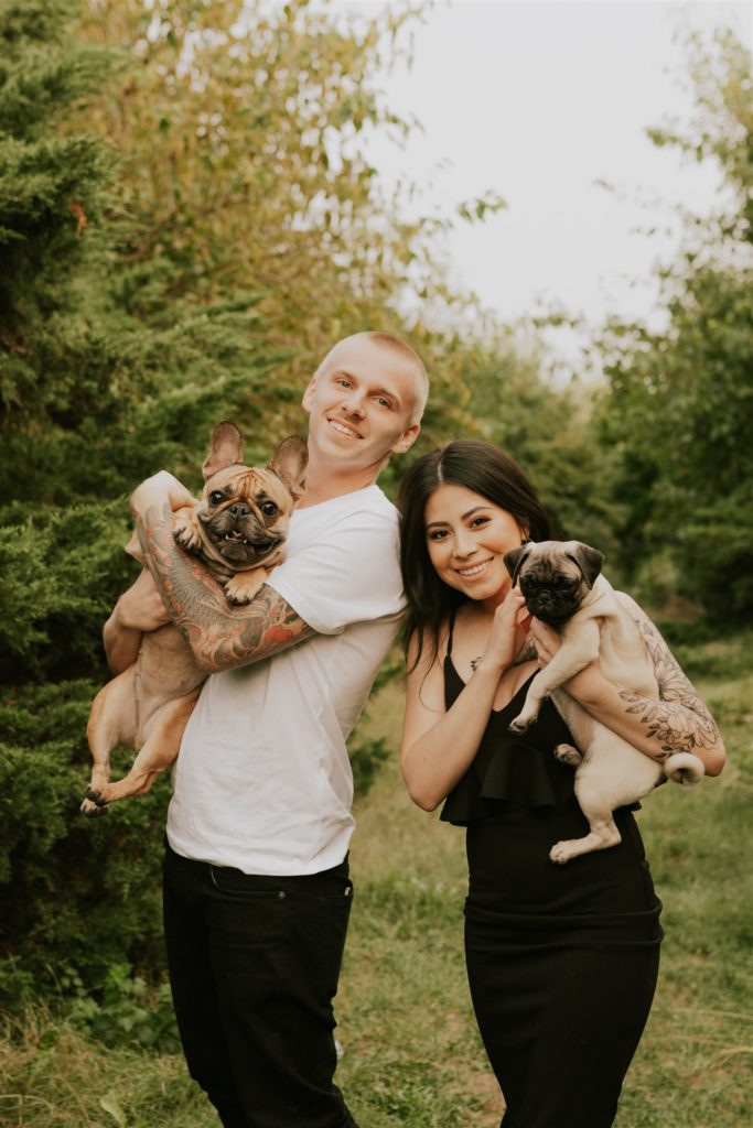 man and woman posing with puppies during engagement session