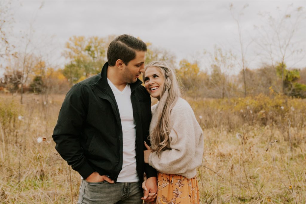 Man and woman in Omaha field posing and laughing during engagement session