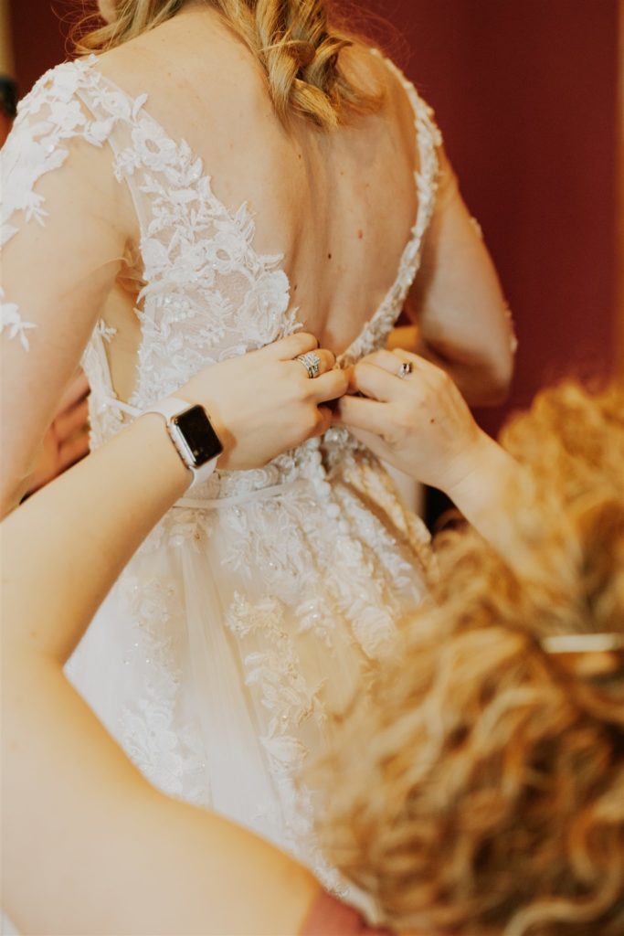 bride getting buttoned up in her dress before wedding ceremony and getting memorable getting ready pictures taken