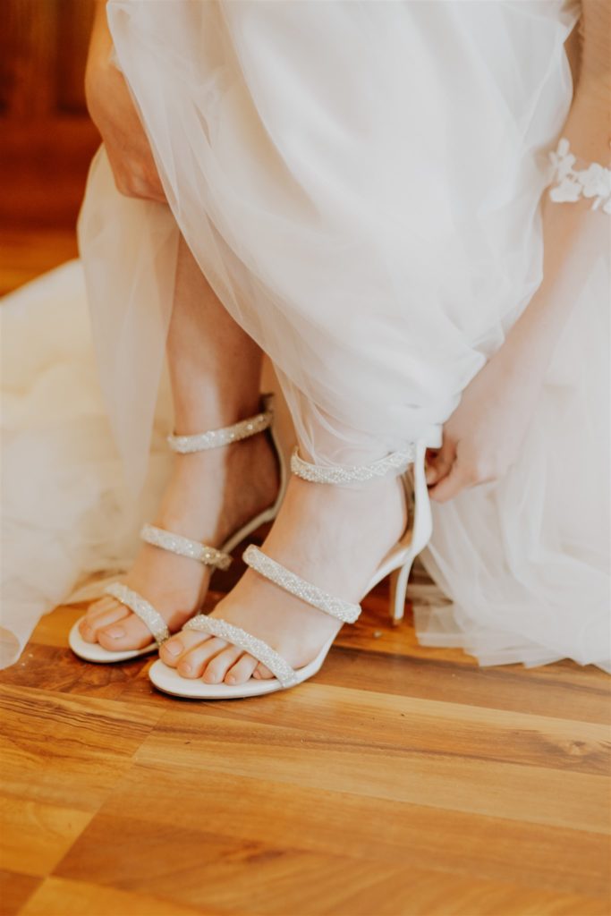 bride putting shoes on before wedding ceremony in omaha