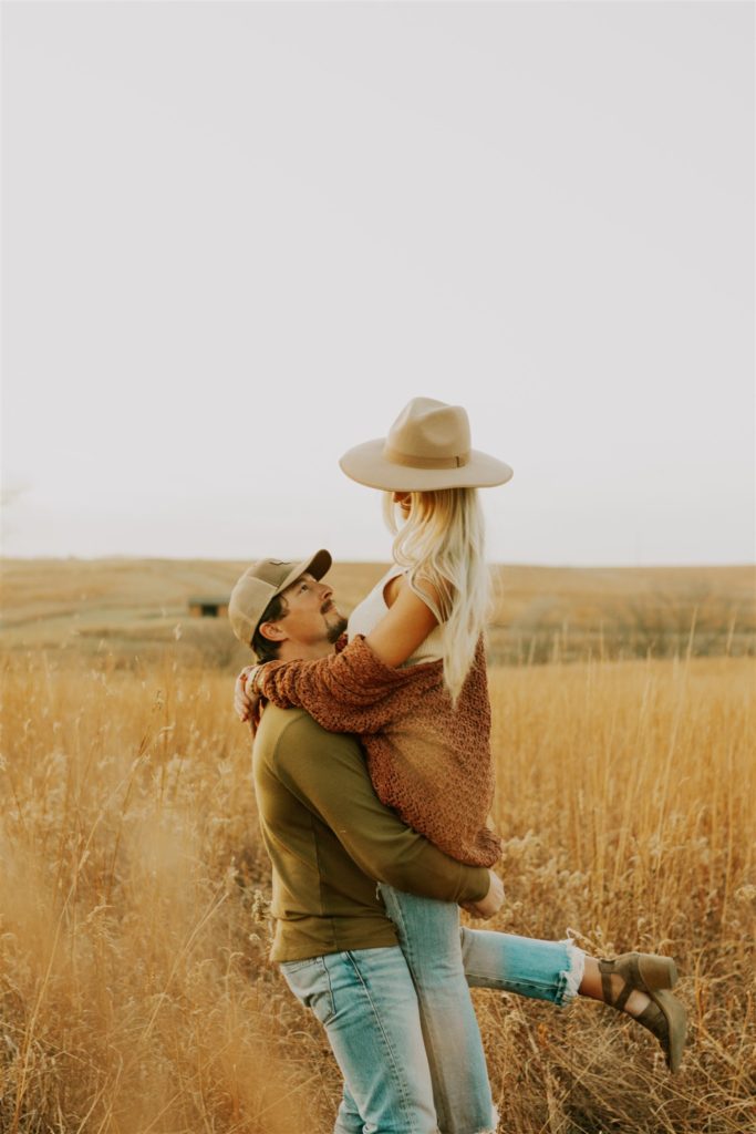 man lifting woman up during outdoor engagement session
