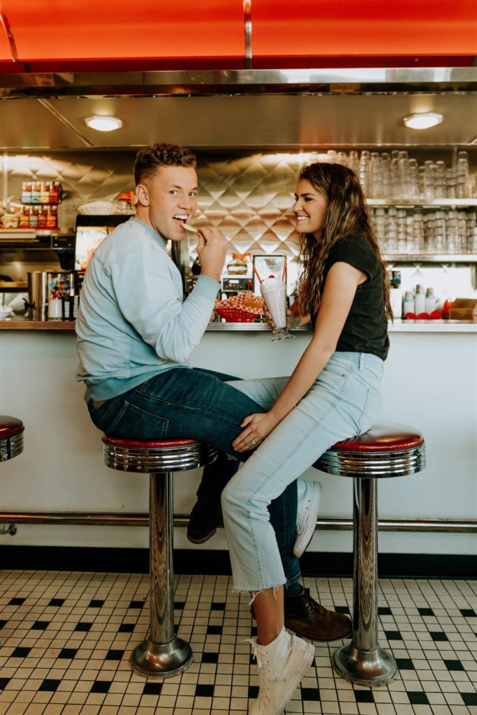 Man and woman in diner eating a milkshake and laughing together