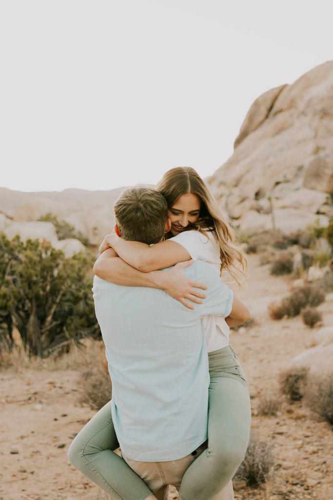 Woman hugging man and wrapping legs around his waist in Joshua Tree couple session