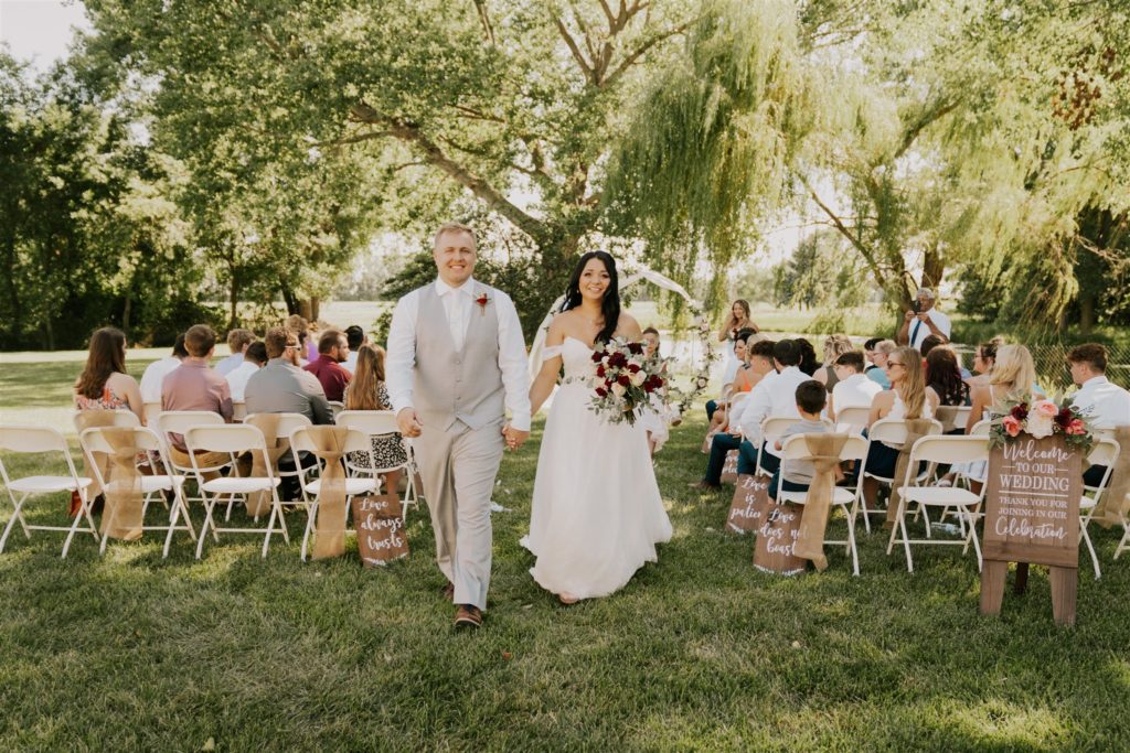 bride walking down aisle with father during backyard wedding in omaha