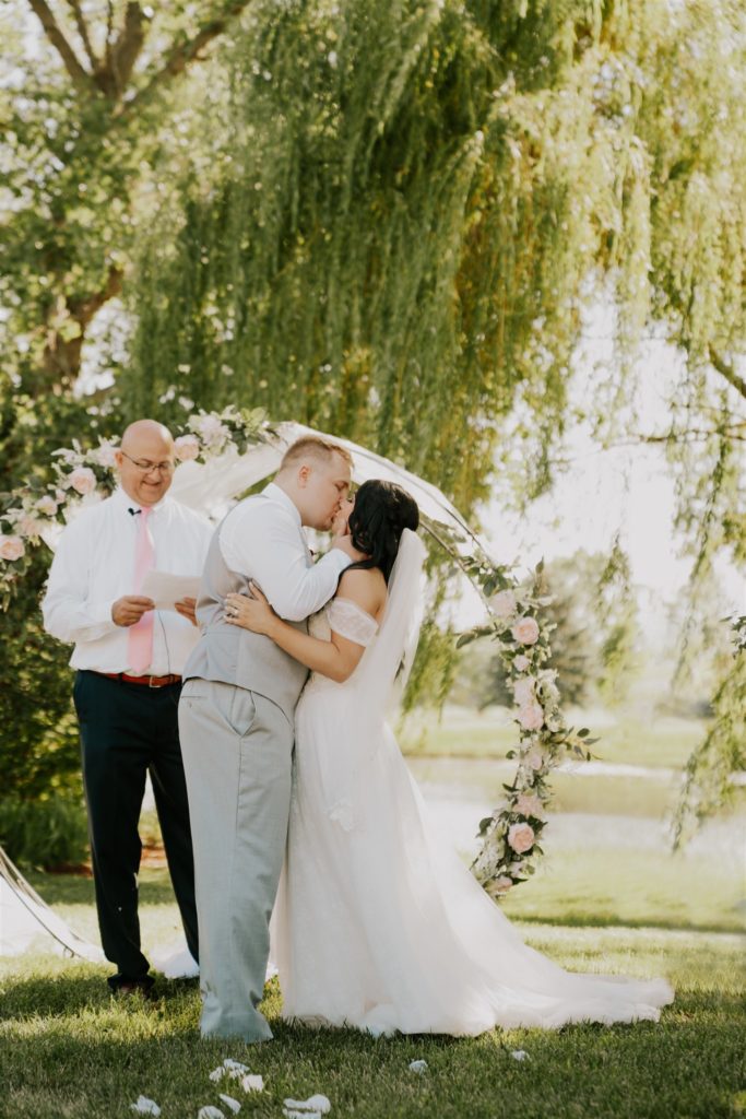 bride and groom kissing after being announced husband and wife during backyard wedding