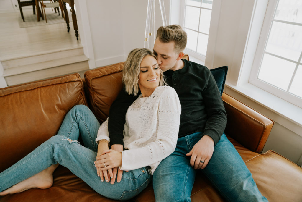 man and woman cuddling on couch during idaho engagement session