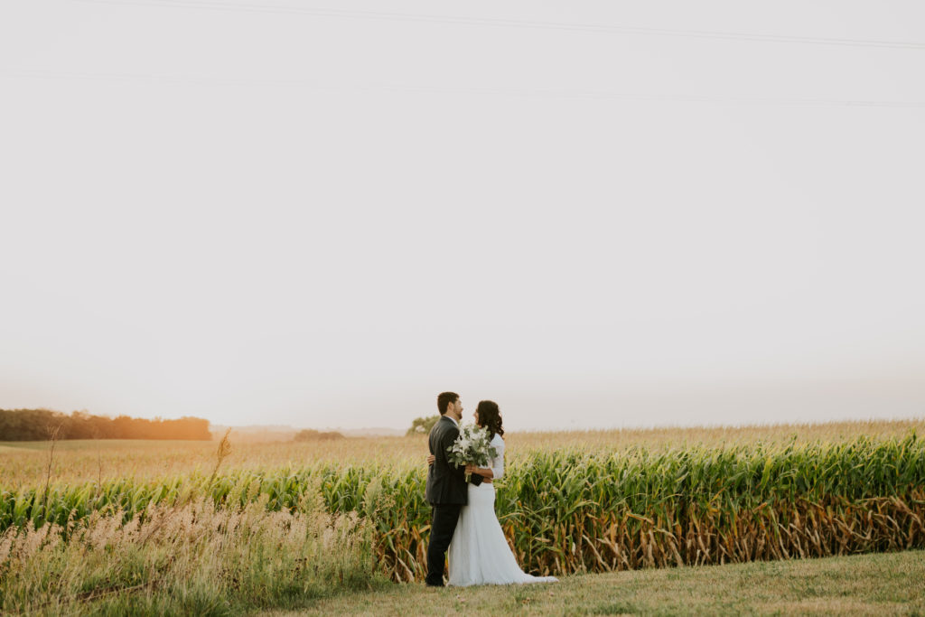 bride and groom posing in front of golden wheat field in Omaha Nebraska bridal session