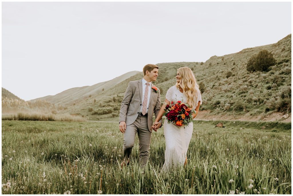 bride and groom walking through idaho field during outdoor bridals session
