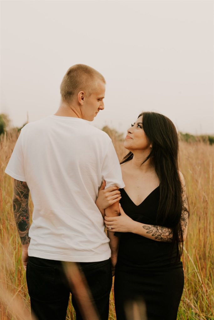 man and woman posing in omaha field during fall couples session