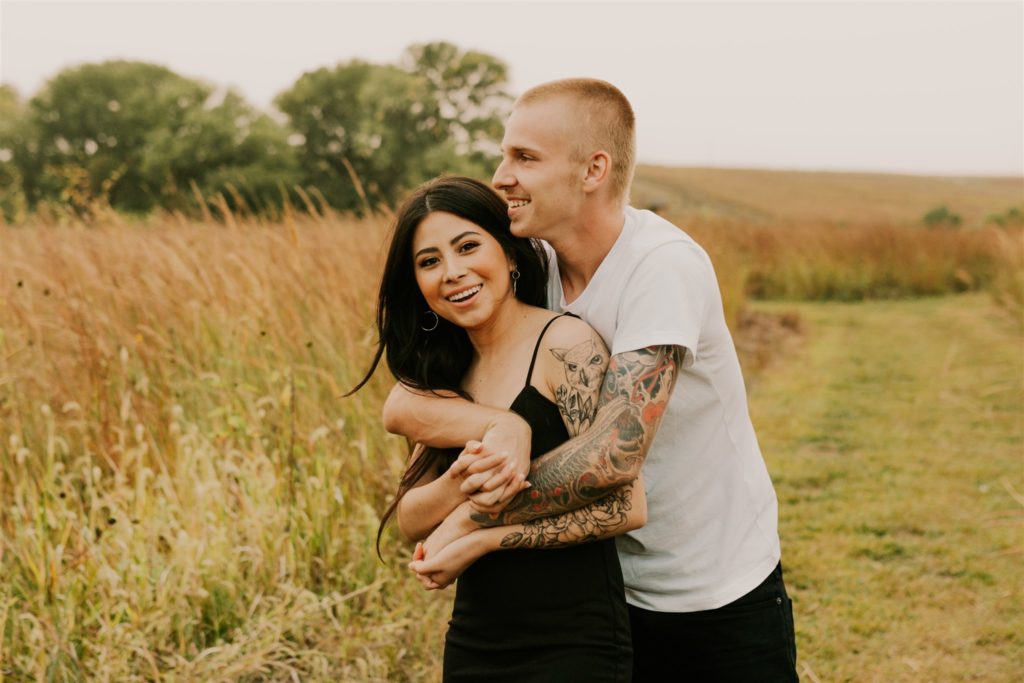 couple hugging and playing in field during fall couples session