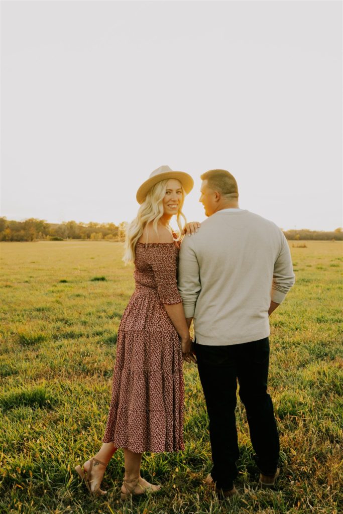 woman looking over man's shoulder in Nebraska field during engagement shoot