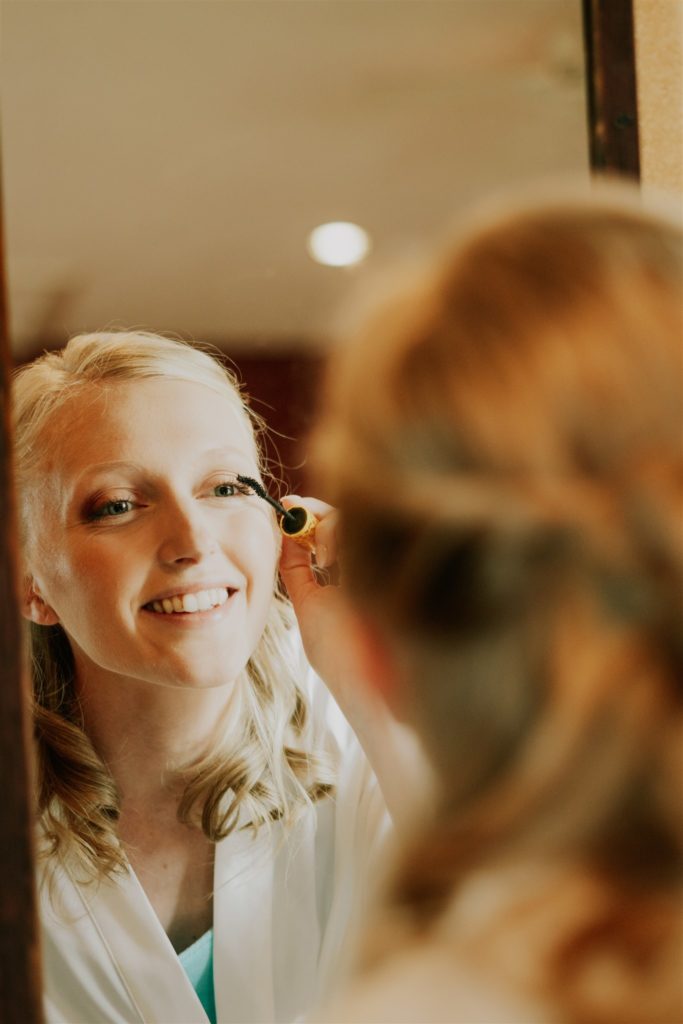 bride putting makeup on before wedding and getting memorable getting ready pictures taken