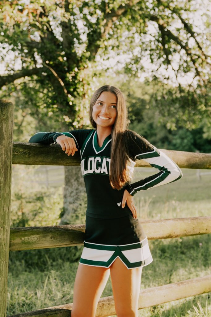 young woman wearing cheer uniform smiling and laughing during omaha senior sessions