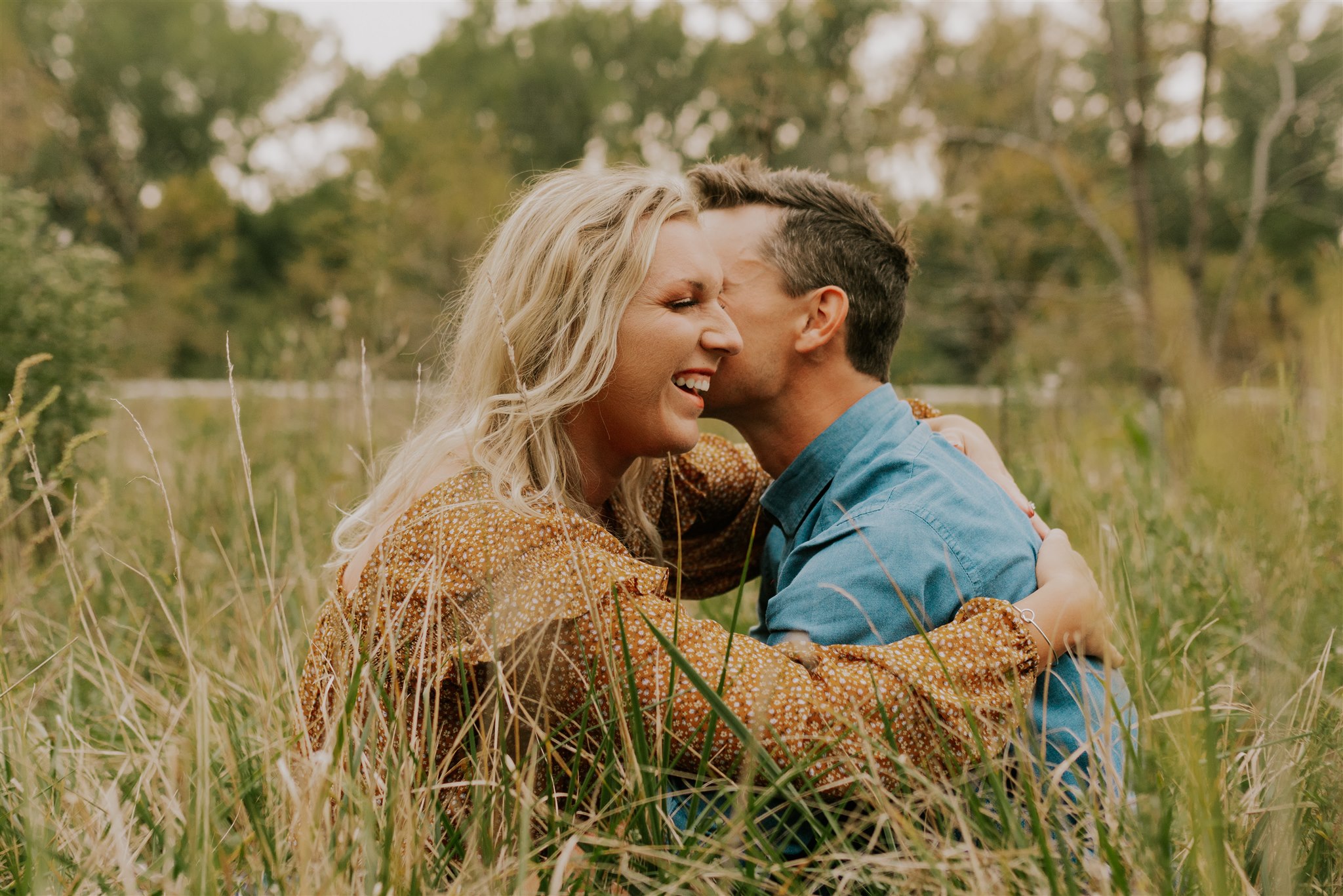 man and woman sitting in grassy omaha field during engagement session