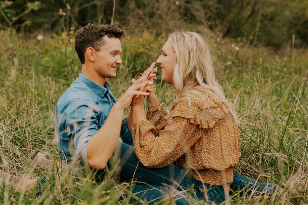 man and woman holding hands in omaha field engagement session