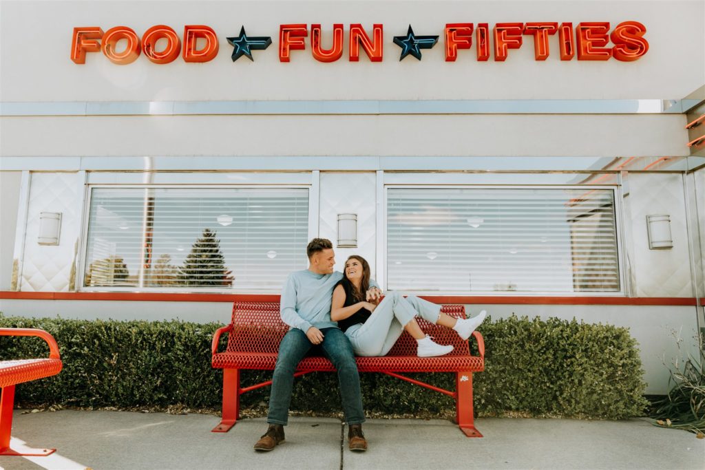 couple posing on bench outside drive in during couples session
