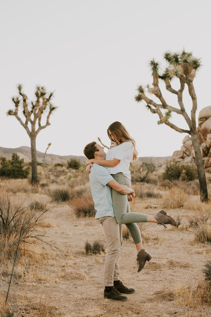 Man lifting woman and holding her up during Joshua Tree couple session