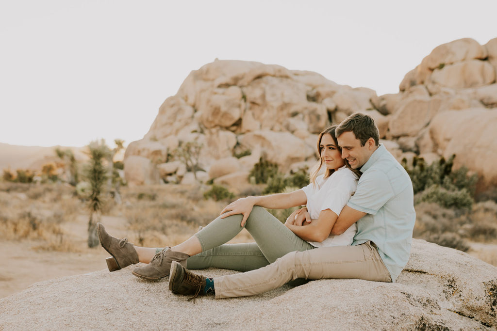 Man and woman sitting together and cuddling on boulder